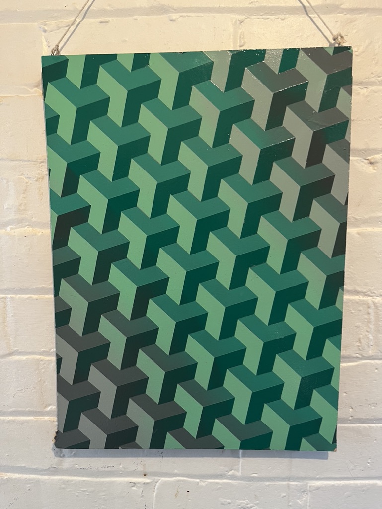 geometric pattern in green and grey spray paint on discarded wood